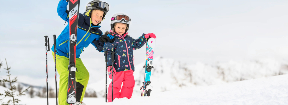 Kinder in Skianzügen beobachten die Berge