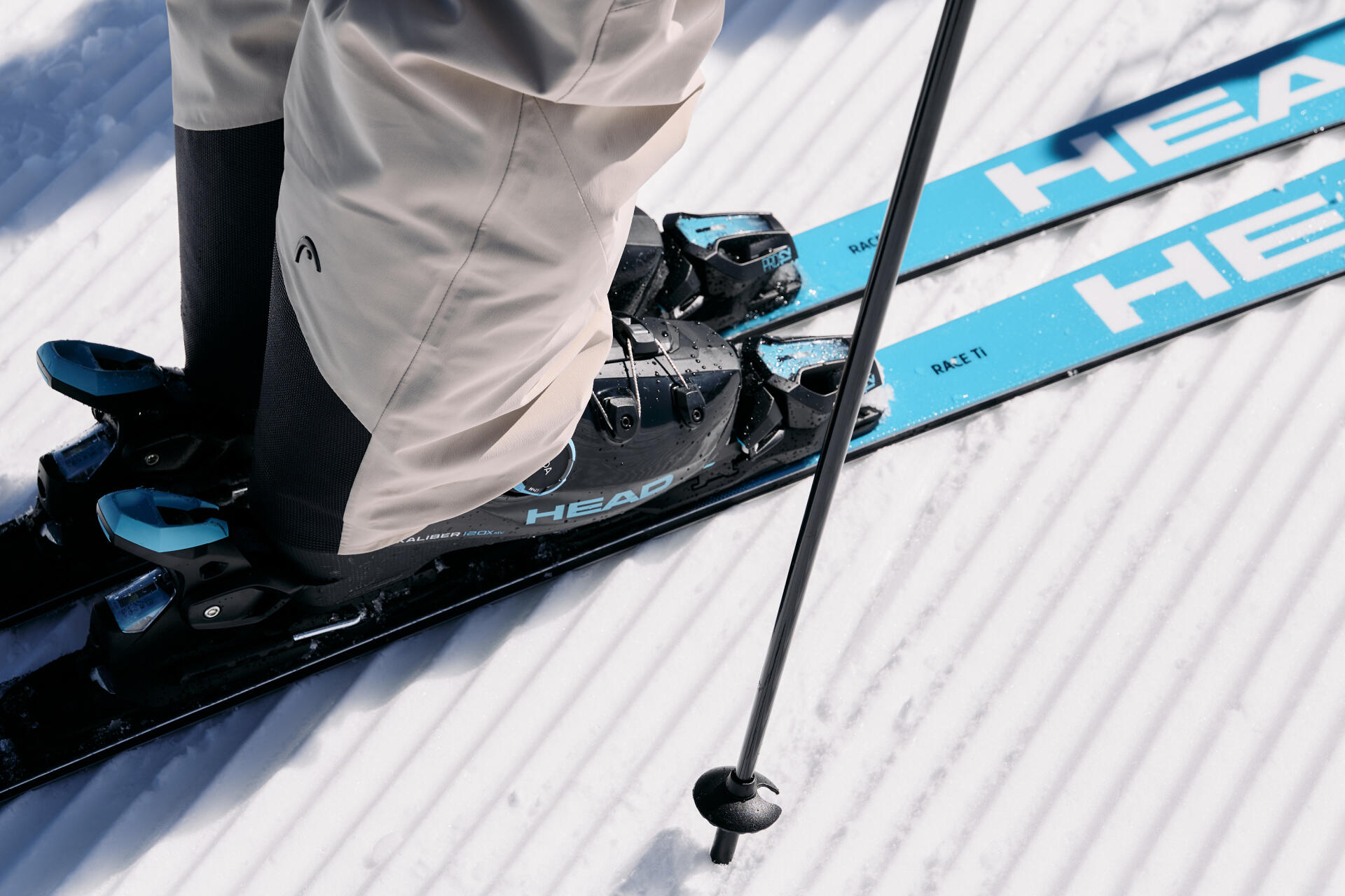 Nahaufnahme eines Skischuhes und eines türkisen Skis
