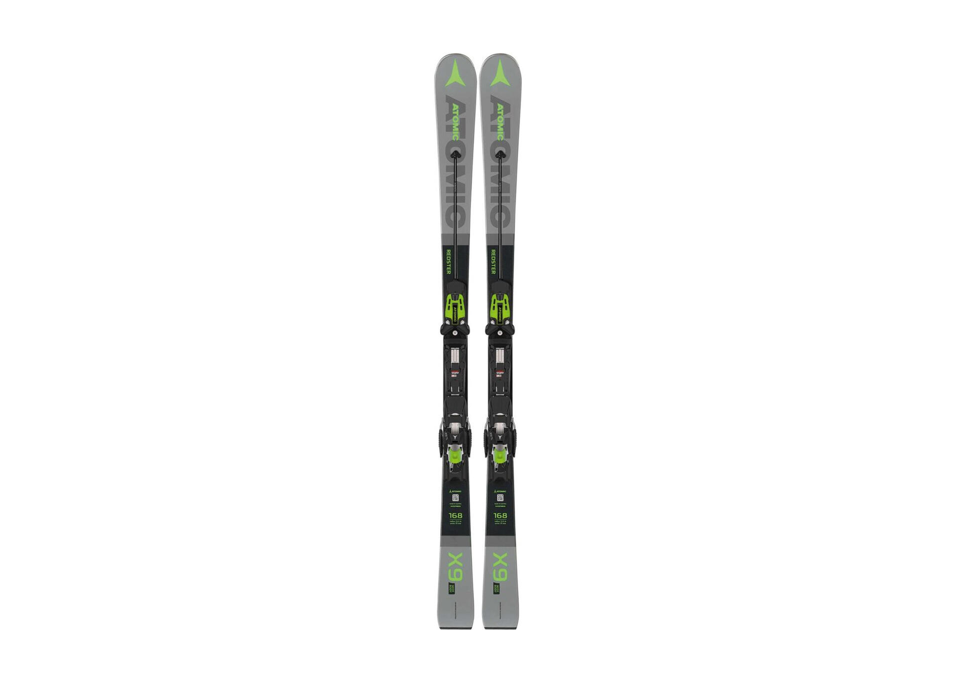A pair of slim, gray-black skis with green accents and bindings stand upright on a white background, showcasing a modern, sporty design.