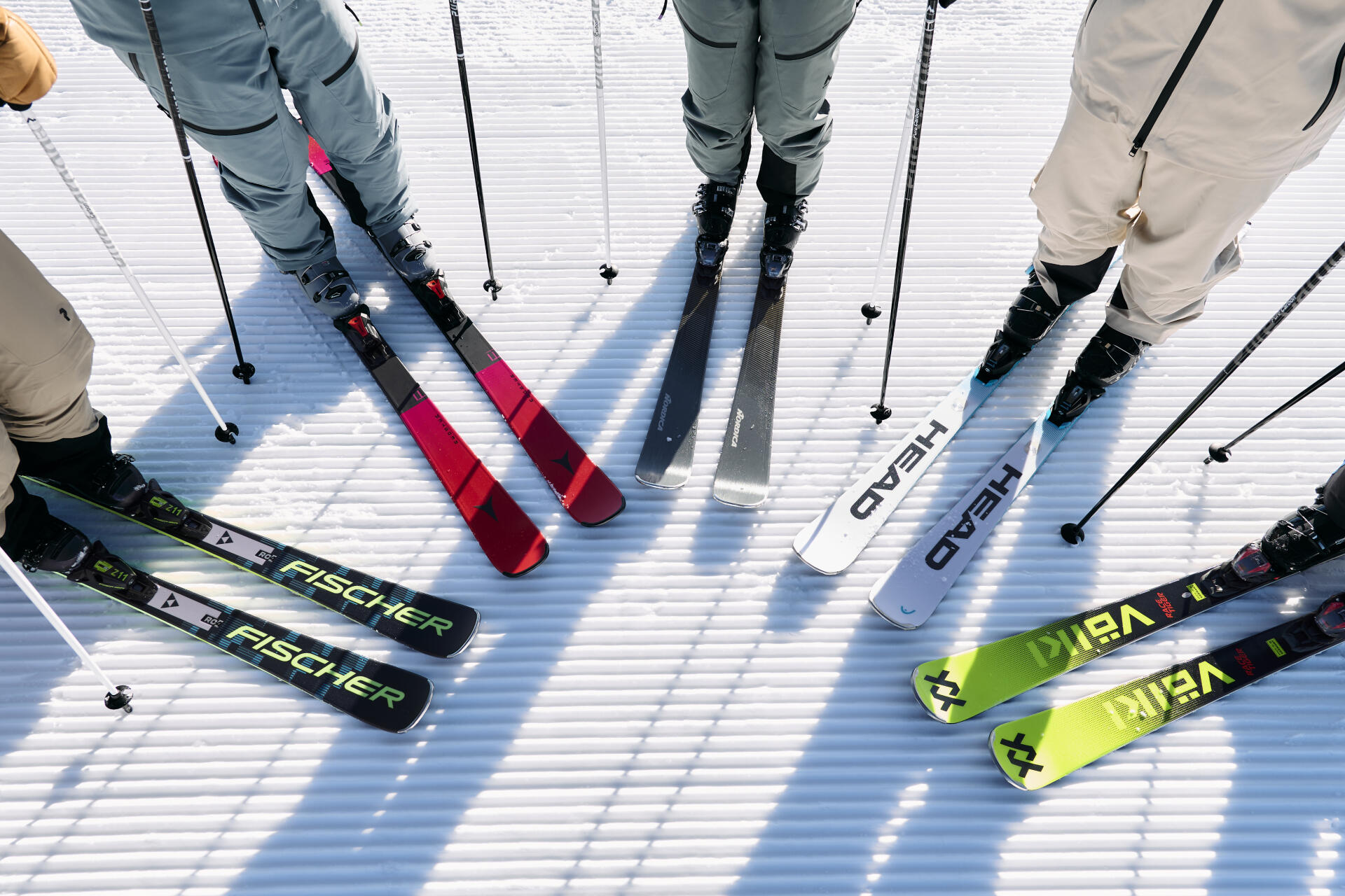 View of skis from different brands belonging to four skiers