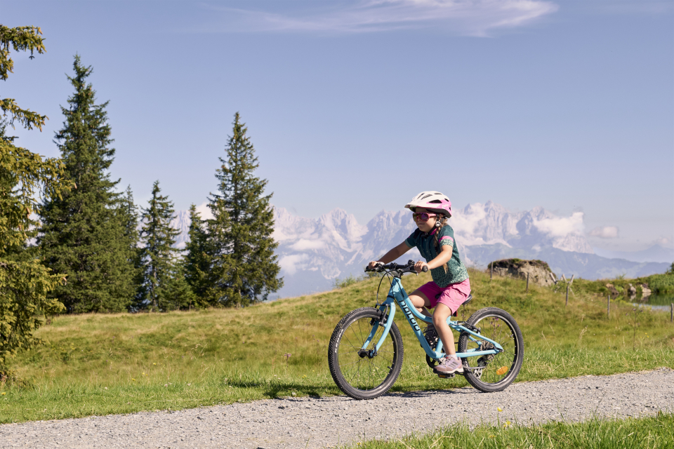 A small child wearing a helmet rides a rental bicycle.
