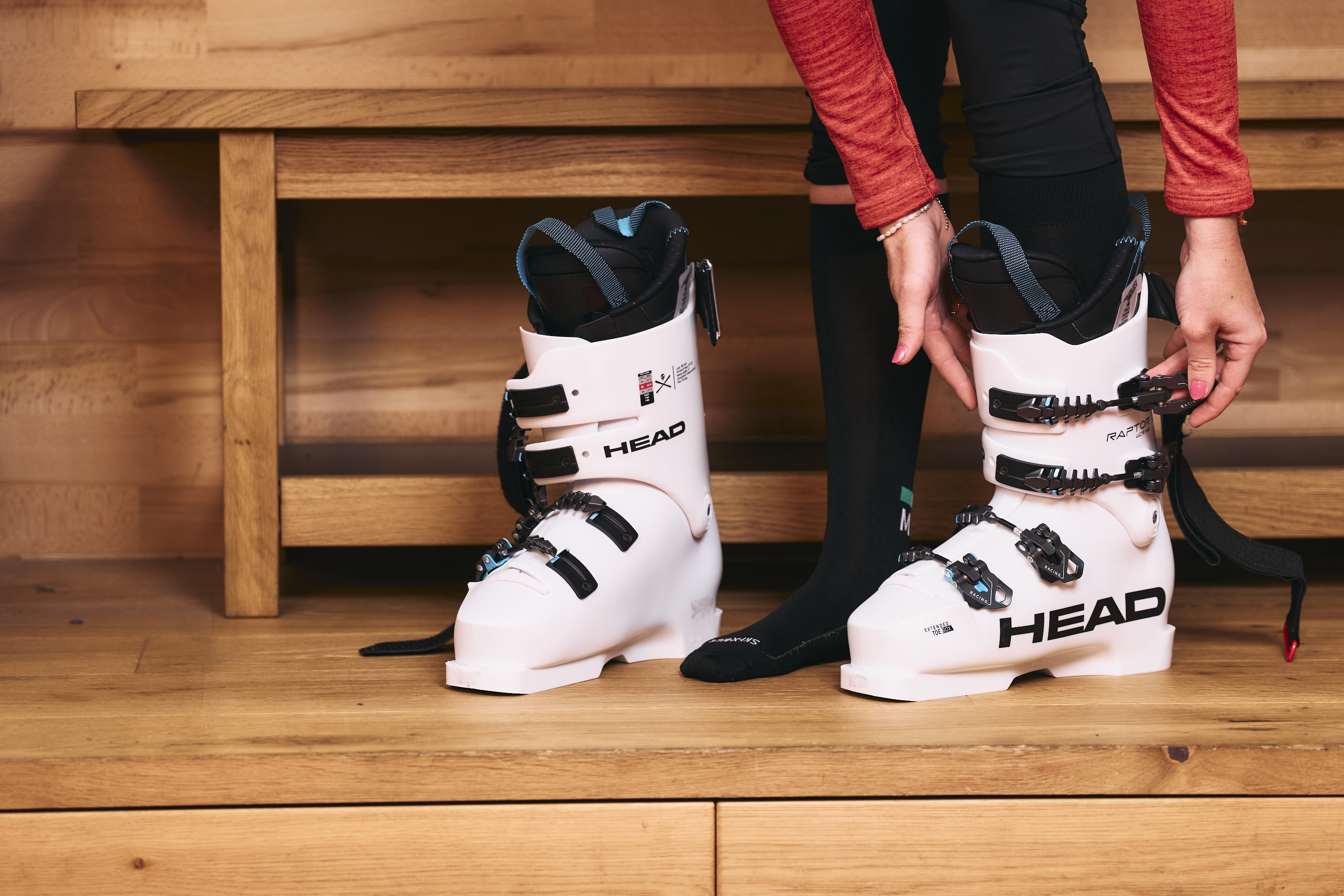 A person puts on white ski boots.